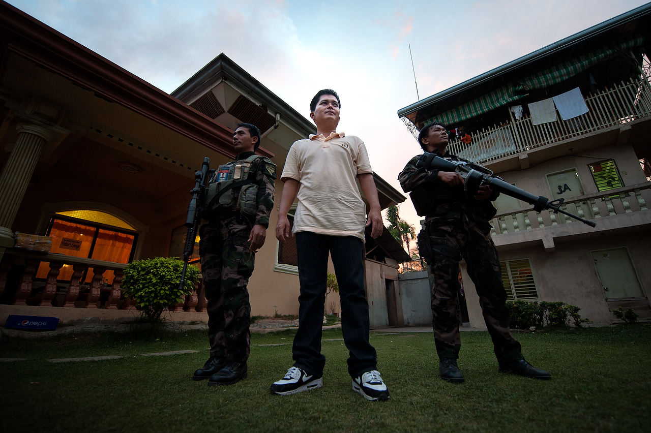 Zamboanga del Sur, Mindanao Philippines.Willson Nandang, the Liberal party candidate for mayor of Pagadin city  stands between two armed police officers in his family house in Pagadin city. Mr. Nandang claims to have escaped attempt on his life. his killing allegedly was ordered by the family of the current mayor. He claims to have been ambushed by the Philippine National Police (PNP) captain Oscampan Buinaopra who still is in the PNP service. Dozen of supporters of the Liberal party candidate for mayor Willson Nandang where heading to campaign rally when group of armed men in bonnets ordered supporters to leave the scene while they killed a driver, Abubakar Padino Somal (47) was killed in Nuburan village, Langapod municipality. Number of killed persons from Langapod municipality is six while several dozens were injured since the election campaign started in Zamboanga del Sur, Mindanao.Intimidation, harassment and killing of the supporters of the political rivals in Mindanao are increasing amid impending presidential and general elections in Philippines. Political dynasties of powerful clans in Mindanao, southern restive province of Philippines, continue to use private armies to intimidate supporters of the rival candidates.