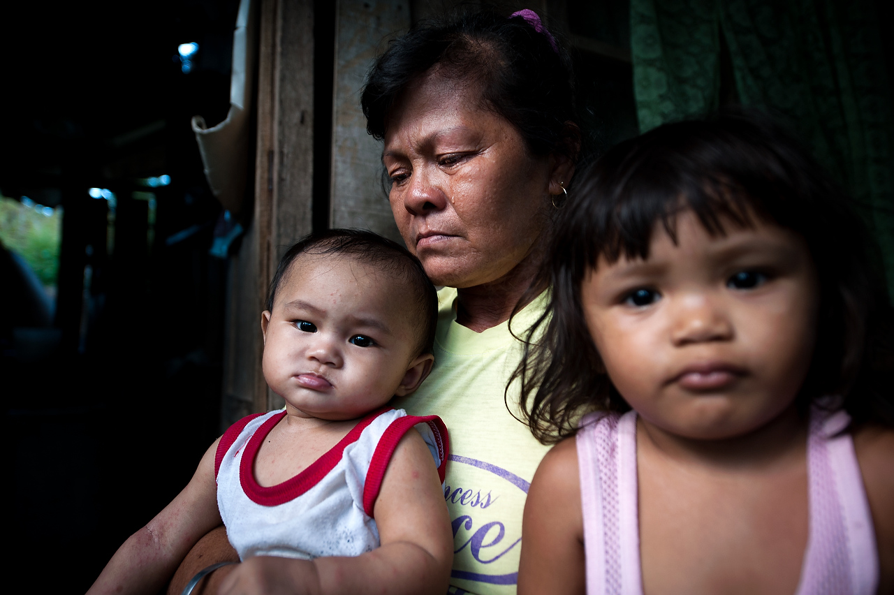 Labangan, Zamboanga del Sur, Mindanao Philippines.Noria Gonzagon Samal (46) wife of the killed driver  cries while holds two minor children.Dozen of supporters of the Liberal party candidate for mayor Willson Nandang where heading to campaign rally when group of armed men in bonnets ordered supporters to leave the scene while they killed a driver, Abubakar Padino Somal (47) was killed in Nuburan village, Langapod municipality.Intimidation, harassment and killing of the supporters of the political rivals in Mindanao are increasing amid impending presidential and general elections in Philippines. Political dynasties of powerful clans in Mindanao, southern restive province of Philippines, continue to use private armies to intimidate supporters of the rival candidates.