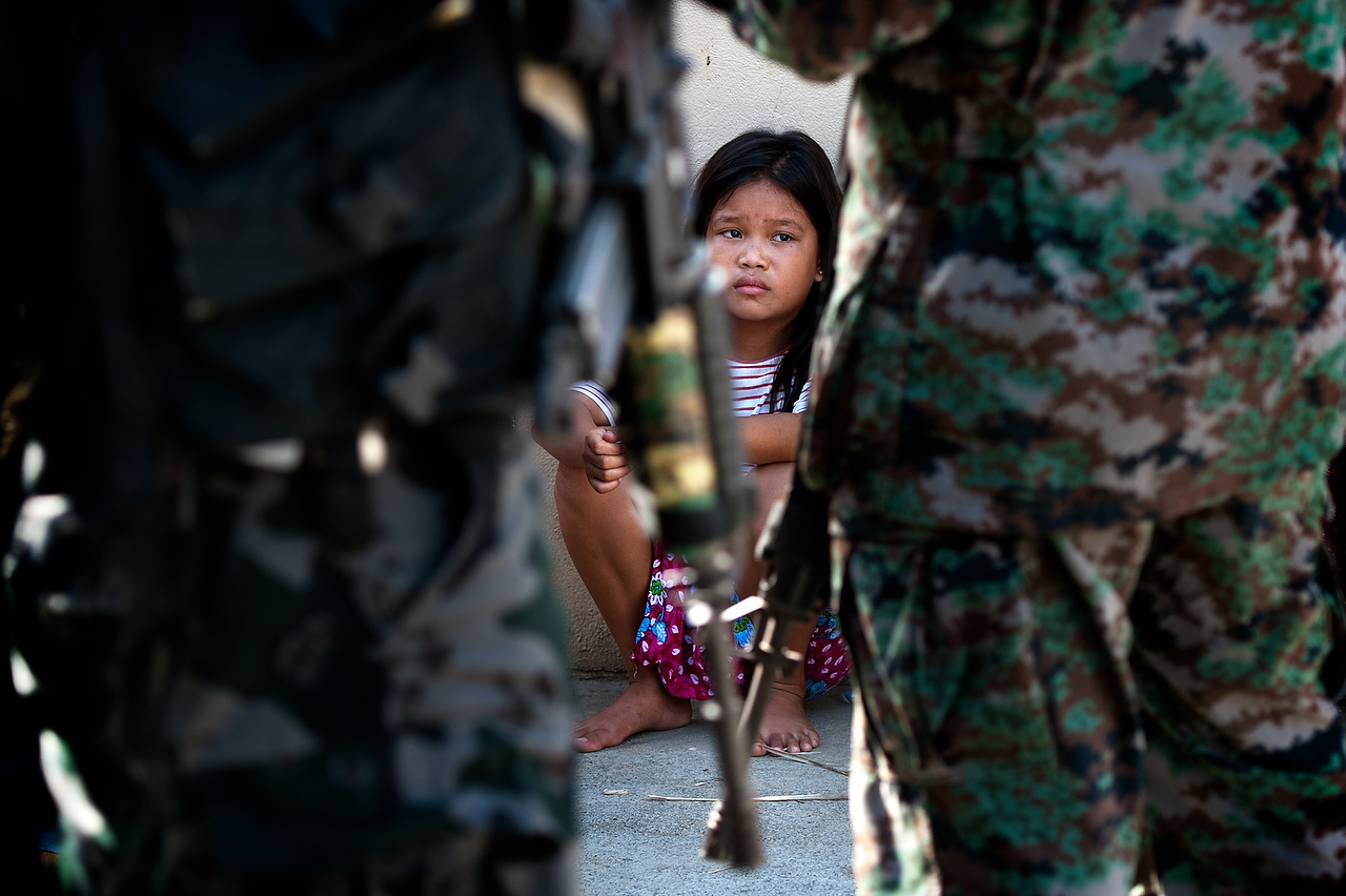 A child watches members of the special police force during the raid which was allegedly orchestrated by the opponent political candidate during the election campaign in Maguindanao.