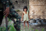 A child watches as the CAFGU member marches past her house. CAFGU paramilitary operate in vicinity of MILF rebel held territory. Often there is exchange of fire as patrols run into each other.