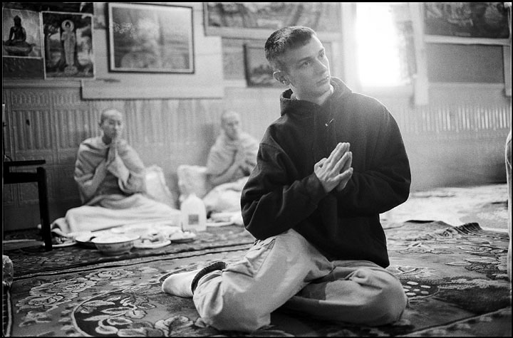 A young man visits the temple to pray with his friends (in the background) who have taken temporary ordination during the funeral of their grandmother. Temporary ordination is taken in order to benefit the future lives of their grandmother.