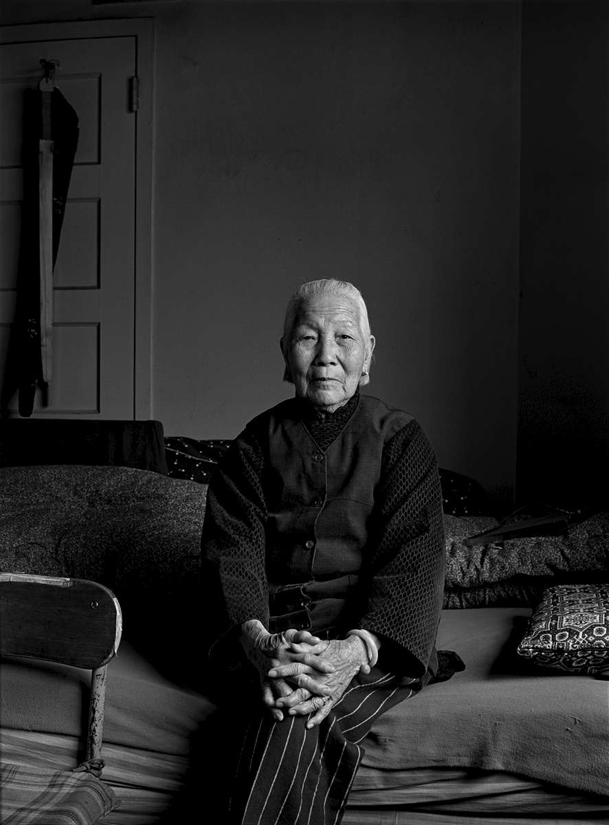 Mrs. Chiu, an elderly Chinese woman, sits on the bed  in her apartment on Pearl St. in New York Chinatown, 1981.