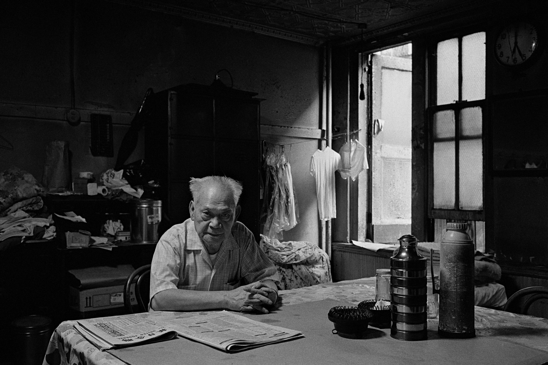 Mr. Ng sits at the table in the apartment he shares with 3 other men, Bayard St., New York Chinatown, 1982