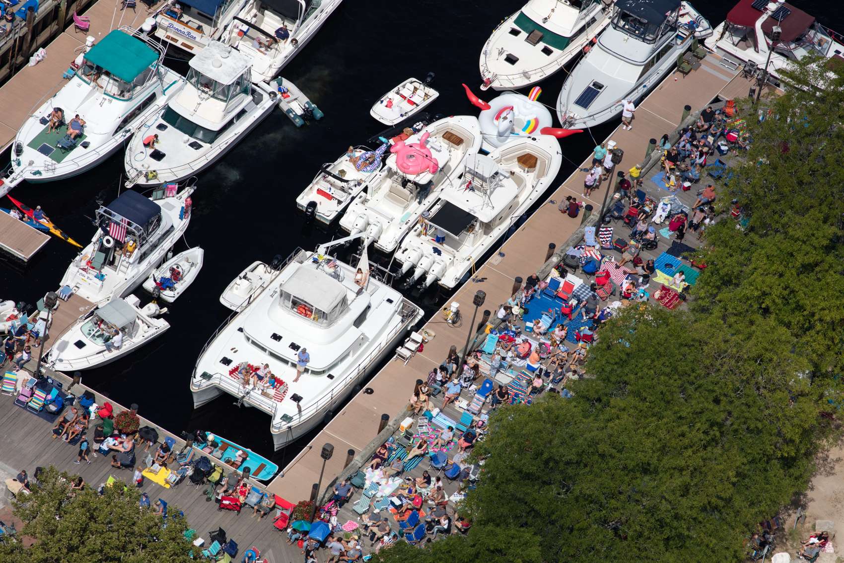 Luxury yachts and high power speed boats with multiple outboard engines rafted together at a music festival in Newburyport, Massachusetts.