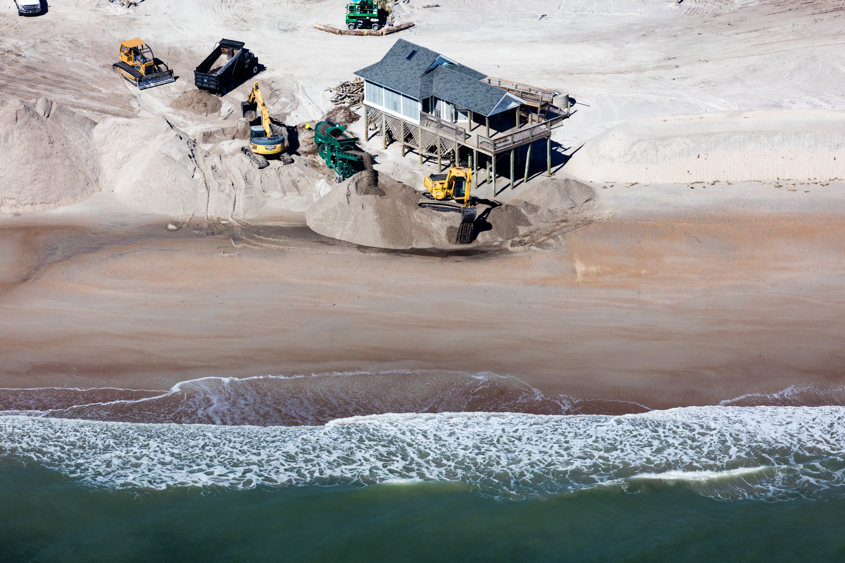 Loads of sand are trucked to North Topsail Beach, North Carolina, to replenish the beach and combat erosion that puts a park building at risk.