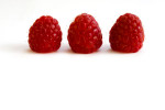 3 red raspberries on white background