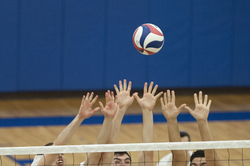 Volleyball players jump for the block during the game against Yeshiva University