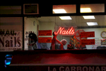 Late evening scene of a nail salons located alongW14th Street NYC. A customer gets a neck massage while her nails dry.