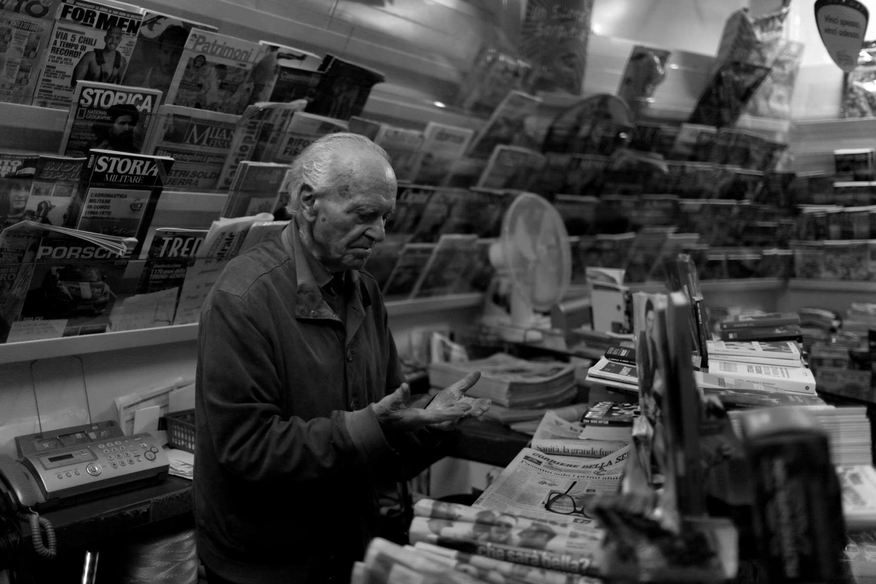 On Sunday, October 22, 2023, Piero Scartoni, 91, pauses to look at the newsprint on his hands.  His daughter Cristiana has told him that someone else is coming in the next week to take over the managing of the newsstand.  It has been difficult to find anyone willing to take Scartoni's place and now someone has been found. 