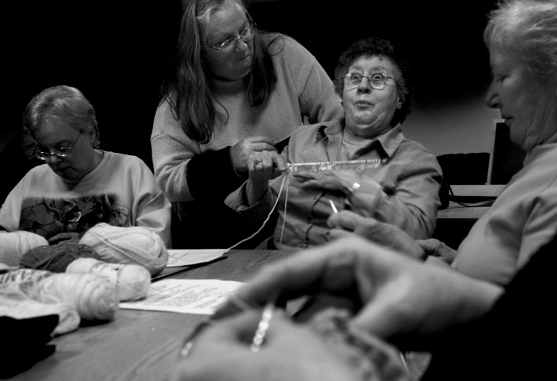 Beth Hartke (standing) inadvertently startles fellow knitter Loraine Fulton as she comes by to check on Fulton's work during a knitting circle at Brainerd Library in Haddam, Connecticut. 