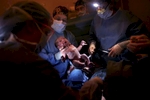 Dr. Michael Bourque hands a baby over after it was delivered in an emergency cesarean.