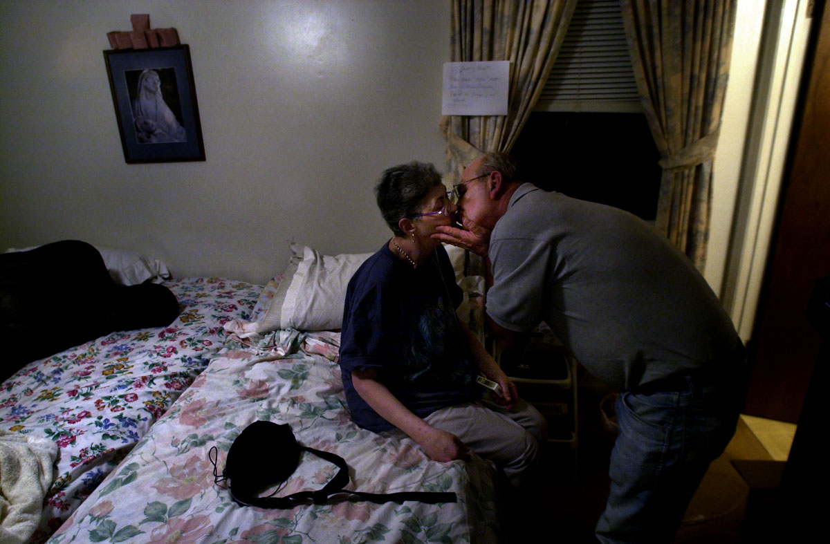 Mike Morin bends to kiss his wife, Gloria, before tucking her into bed. The two have been married for almost 30 years.