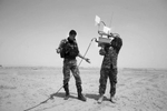 Nawfal Hotaf, left, wonders the best way to hold the antenna to operate the robot while working with Ahmad Shalal, right as they work with the Navy's Explosive Ordnance Disposal Mobile Unit 2 in Iraq at COB Speicher during a training exercise. Both men are with the Iraqi Police and are working with explosives removal in Iraq.
