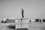 A soldier with the Virginia National Guard stands on top of a garbage container to try to get a better photograph at Camp Adder in Iraq.
