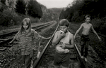 Amanda, Alan and Clifford walk along the railroad track behind their house after collecting some apples from a tree.