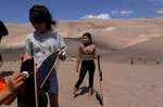 Puja Rai, 14, left and Sapana Gurung, 14, right, prepare to ride down some of the dunes on Sept. 2, 2017. The crew spent a large part of the day at the Great Sand Dunes National Park and Preserve.