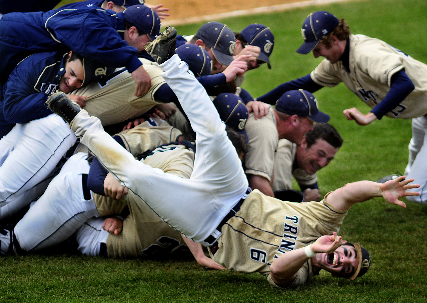 Trinity College's Kent Graham (6) rolls off a pile of teammates as they erupt with excitement after they won the championship game in the NCAA Division III New England Regional Tournament against Eastern Connecticut State University.  Trinity won 5-4. 