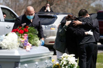 Everett, MA - 4/29/20 - Family members embrace as other mourners look on from the car during the funeral service for Santos A. Rivas at Woodlawn Cemetery in Everett. Due to strict social distancing guidelines only ten people are allowed outside of the car for graveside services at Woodlawn Cemetery in Everett. Friends and family lined three sides of the street surrounding the gravesite to pay their respects to Santos A. Rivas, who passed away from coronavirus or COVID-19. (Jessica Rinaldi/Globe Staff) 