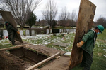 Everett, MA--12/8/20-- Roberto Arias (R) and Sean O'Donnell move pieces of wood in order to cover a grave that they've prepared for a burial that will take place the following day at Woodlawn Cemetery for a man who died of COVID-19. 