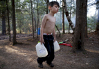 Oxford, Maine -- 5/4/2015--  Strider carried gallon jugs of water over to Lanette after filling them from a spigot behind the camper so that she could wash dishes and heat some of it on the small stove inside to bathe the boys with a washcloth. Jessica Rinaldi/Globe Staff