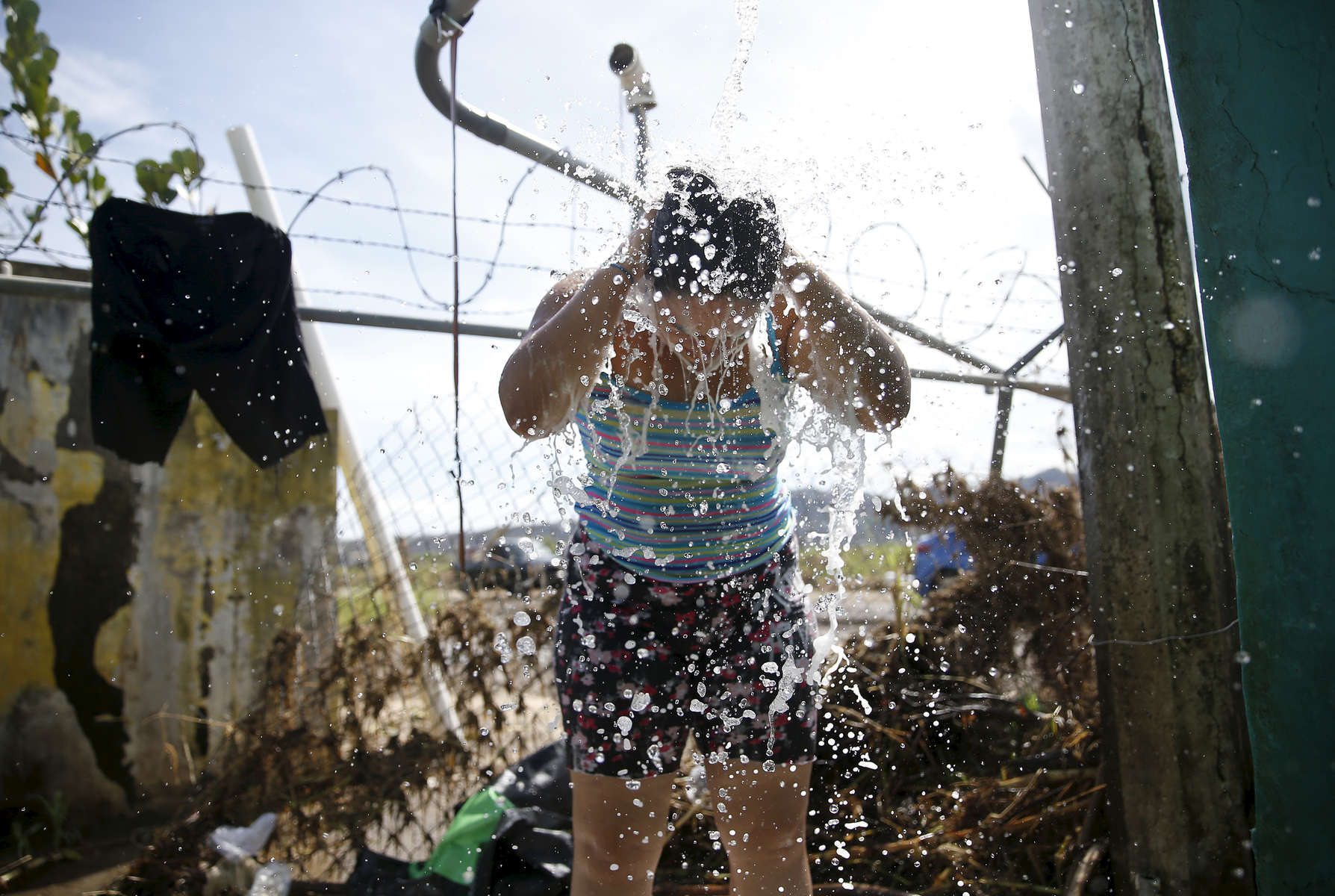 Arecibo, Puerto Rico -- 10/01/2017 -  With aid and supplies slow to come to this corner to the island, scores of residents in Arecibo like Deborah Estremera, came to bathe and wash their clothes in one of the few available spigots of fresh water here. They knew it was unsafe to drink but still filled jugs so that they could flush toilets and clean their homes. 
