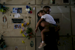 Corozal, Puerto Rico -- 10/02/2017 -  Orlando Gonzalez holds his daughter, Nahielys, inside a mausoleum at their neighbor, Victor Ruiz's funeral. After the storm had knocked power out on the island, Ruiz had been using his car to charge the machine that helped him treat his emphysema. When he started to run low on fuel he went to a nearby gas station. He had waited over 35 hours in line when a nearby explosion sent a plume of smoke up into the air, causing the gas station to be evacuated. Ruiz made it home, but died in his car before he could get out. The death count has not included people like Ruiz, whose death was an indirect result of Hurricane Maria.
