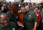 Selma, Alabama -- 3/08/2015-- (L-R) Kevin Peterson of the New Democracy Coalition, UMass student Vonds Dubuisson, 27, smile as Gloria Patterson, of Detroit hugs Joanne Bland, of Selma who was one of the original marchers  who marched with Dr. Martin Luther King, Jr. over the Edmund Pettus Bridge on Bloody Sunday, as her older sister, Lynda Blackman Lowery laughs as Patterson appears on a documentary playing out over the crowd of people ready to retrace the steps of those who marched with Dr. Martin Luther King, Jr. over the Edmund Pettus Bridge 50 years ago in Selma, Alabama March 8, 2015. 