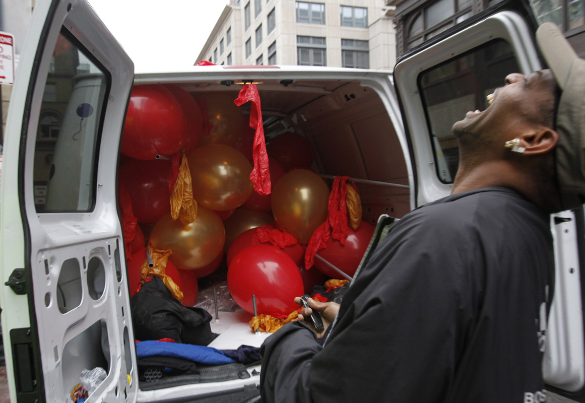 A man transporting balloons laughs as police officers watch him pop the remaining balloons in order to make the used arrangement fit inside his delivery van in the Chinatown section of Boston, Massachusetts June 4, 2012.