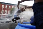 A woman swings a child through the spray from a fire hydrant during a heat wave in the Bushwick section of Brooklyn, New York July 6, 2010. 