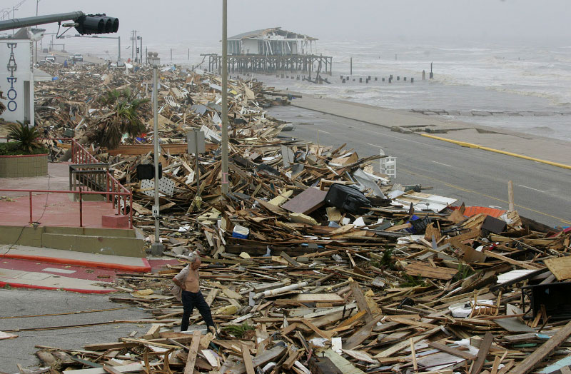 A man walks amid debris from Hurricane Ike that was cleared from the road in Galveston, Texas September 13, 2008.