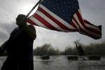 Robert Shumake holds an American flag as high swells caused by Hurricane Ike break behind him in Galveston, Texas September 12, 2008.  Hundreds of thousands of people fled coastal areas in the path of Hurricane Ike on Thursday as the storm gathered strength on a collision course with the Texas Gulf Coast, threatening to swamp populous areas around Houston under a massive wave of water. 