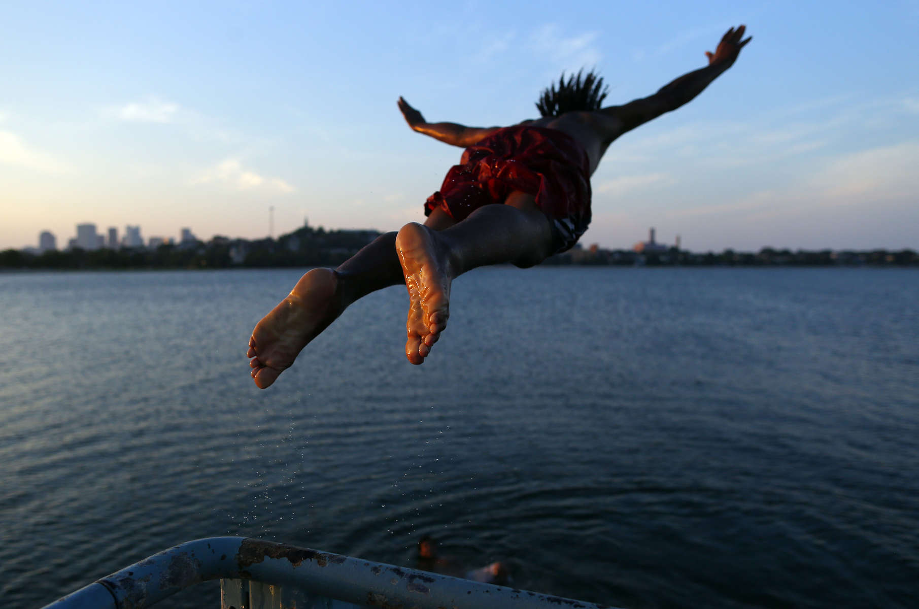 South Boston, Massachusetts -- 07/08/2014--   Edson Pontes, of Dorchester leaps off of a pier into Old Harbor in South Boston, Massachusetts July 8, 2014. Jessica Rinaldi/Globe StaffTopic: 09featureReporter: 