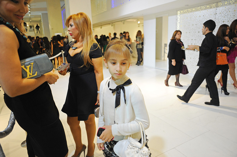 BAKU, AZERBAIJAN.  A young girl stands beside her mother and a friend at the grand opening celebration of Emporium's second store at the Port Baku luxury residences on October 28, 2011.  Emporium's second store in Baku was designed by Japanese architect Yukio Ishiyama of the Milanese design firm Garde and features over 150 luxury ready-to-wear brands such as Azzedine Alaïa, Marc Jacobs and Stella McCartney; Emporium is widely considered to offer the greatest variety of high-end designer shopping in Baku under one roof.