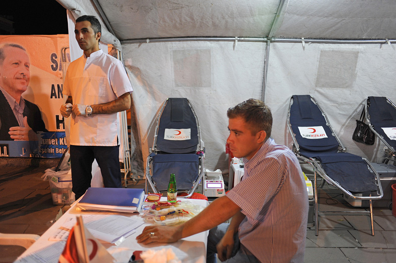 ERZURUM, TURKEY.  A male nurse stands over a man after giving blood at a blood drive organized by the Turkish Red Crescent in a tent on Cumhurriyet Road in Erzurum, Turkey, the first major city near the route of the Baku-Tbilisi-Ceyhan oil pipeline in Turkey, located just 10 kilometers from the pipeline which traverses numerous villages near the city's airport, on August 11, 2010, the first night of Ramadan.  During the month of Ramadan, Muslims are encouraged to give Zakat or money for charity, one of the five pillars of the Muslim faith, and those who cannot are instructed to donate blood and perform other acts of charity.