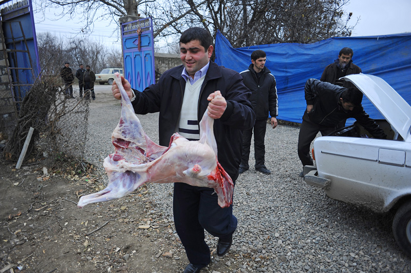 ZAYAM, AZERBAIJAN.  A man takes a lamb carcass from the trunk of a car for butchering before cooking for women mourners during the seven day ceremony, part of Azerbaijan's elaborate funeral rituals that include gender segregated commemorations of the deceased three days, seven days and 40 days after their death in Zayam, Shamkir Region, Azerbaijan, approximately four kilometers from the BTC pipeline, on January 3, 2012.  Compensation funds for land traversed by the BTC pipeline paid to the family of the deceased as a result of disruption stemming from the period of the pipeline's construction totaled under $1,000 and went to keeping the deceased healthy and caring for her daughter who suffers from tuberculosis.