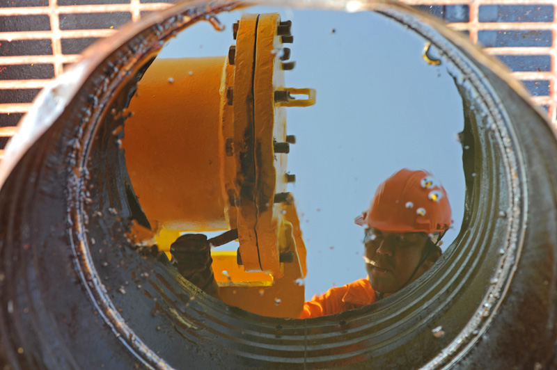 CEYHAN MARINE TERMINAL, TURKEY.  A Philipino worker seen through a bucket to catch leaking crude oil secures a valve after loading Azeri crude oil from the Baku-Tbilisi-Ceyhan oil pipeline onto a Greek oil tanker, The Aegean Myth, on August 16, 2010 before setting sail for Rotterdam, The Netherlands.