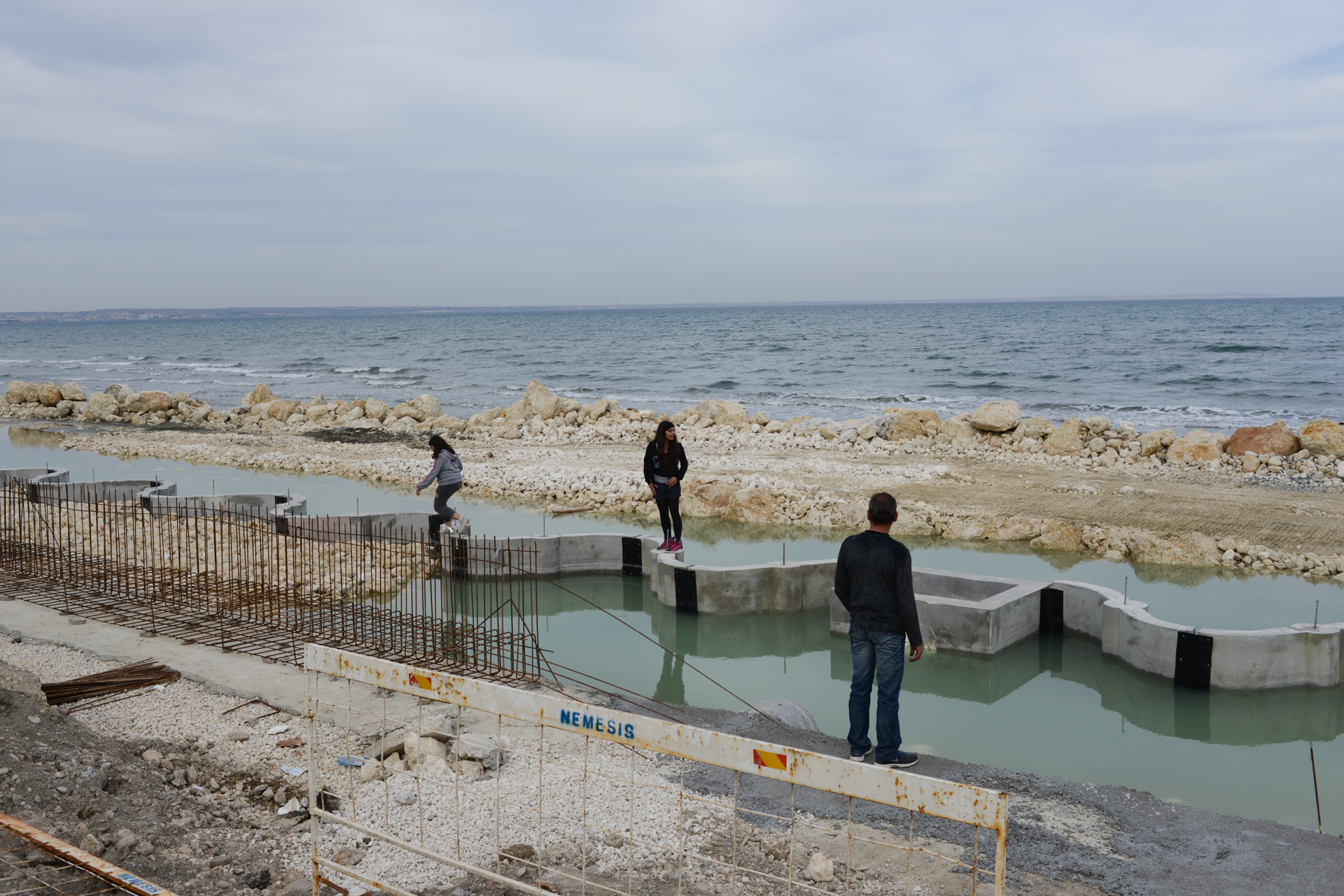 LARNACA, CYPRUS.  People stand on the new break line being used to extend the shoreline out into the sea as it is under construction on March 29, 2013.