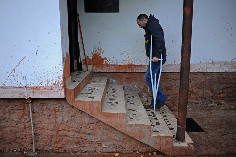 DEVECSER, HUNGARY.  The younger Gyozo Bakonyi enters his parents home in an otherwise abandoned and condemned section of Devecser on November 21, 2010, after an industrial accident sent a torrent of toxic red alumina sludge gushing through Devecser and several nearby villages, killing ten, destroying homes, leaving several families homeless and severely injuring hundreds on October 4, 2010.  Bakonyi survived the accident only to be injured during the clean up the day after; the red marks on the house indicate the height of the sludge at the time of the accident.