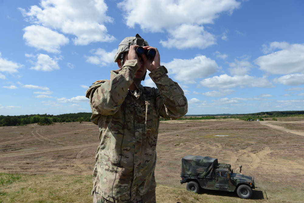 DRAWSKO POMORSKIE TRAINING AREA, POLAND.  Sergeant Stephen Murphy with the Fourth of the 319th Airborne Field Artillery Regiment of the 173rd Airborne Brigade Combat Team monitors an airdrop from a C-17 aircraft that took off from Nuremberg, Germany before it drops members of his unit on June 15, 2015.  NATO is engaged in a multilateral training exercise {quote}Saber Strike,{quote} the first time Poland has hosted such war games, involving the militaries of Canada, Denmark, Germany, Poland, and the United States.