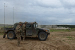 DRAWSKO POMORSKIE TRAINING AREA, POLAND.  American soldiers with the 2nd Battalion, 7th Infantry Regiment, 1st Armored Brigade Combat Team, 3rd Infantry Division based out of Fort Stewart, Georgia beside a Humvee before a live fire exercise with a German-made Danish Leopard 2A5 tank on the horizon on June 16, 2015.  NATO is engaged in a multilateral training exercise {quote}Saber Strike,{quote} the first time Poland has hosted such war games, involving the militaries of Canada, Denmark, Germany, Poland, and the United States.