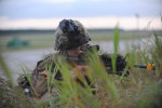 SWIDWIN AIRFIELD, POLAND.  PB2 Michael Simkin with the 1st Battalion, 503rd Infantry Regiment, 173rd Airborne Brigade maintains his position on a grassy knoll after parachuting in from a C-130 during an airfield seizure exercise on June 16, 2015.  NATO is engaged in a multilateral training exercise {quote}Saber Strike,{quote} the first time Poland has hosted such war games, involving the militaries of Canada, Denmark, Germany, Poland, and the United States.