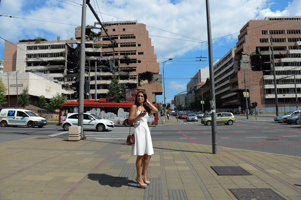 BELGRADE, SERBIA.  A woman stands in front of the former Serbian Ministry of Defense (at left), formerly the Yugoslav Ministry of Defense, and the Army Headquarters (at right), which were hit by NATO bombs in 1999 during the conflict with Kosovo under former Serbian leader Slobodan Milosevic, which have been left since as a morbid reminder of sorts of Serbia's recent past on Kneza Milosa on June 29, 2015.  Part of the Army Headquarters building remains in use.