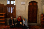 ISTANBUL, TURKEY.  A woman prays as another checks her cell phone inside the Blue Mosque compound in the Sutanahment neighborhood on January 12, 2014.