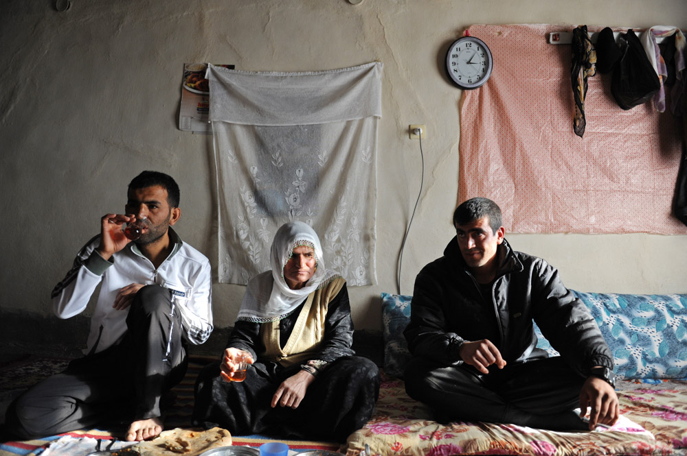 FIS, TURKEY.  Villagers eat lunch and drink tea in their home on February 24, 2012.  Fis is known as one of the first meeting places of arrested Kurdish Workers' Party, PKK, guerrilla leader Abdullah Ocalan;  Fis used to be home to 70 families but the Turkish military destroyed much of the town repeatedly in 1993-1994 in retalliatory strikes for the villagers show of sympathy to the PKK guerrillas who they provided food and shelter to ({quote}They are our sons,{quote} in the words of one villager), and now only seven homes have been rebuilt in Fis after a period of forced exile from the village and everyone is too scared to provide their name.