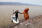 Garrett Dong, right, in costume assists Barbara Bellfield, both of Ventura, Calif., while she exits a paddle baord at Lake Manly, a temporary lake formed by heavy rainstorms, at Death Valley National Park, California, U.S., February 24, 2024. The lake is located at Badwater Basin, which is the lowest point in North America at 282 feet below sea level.