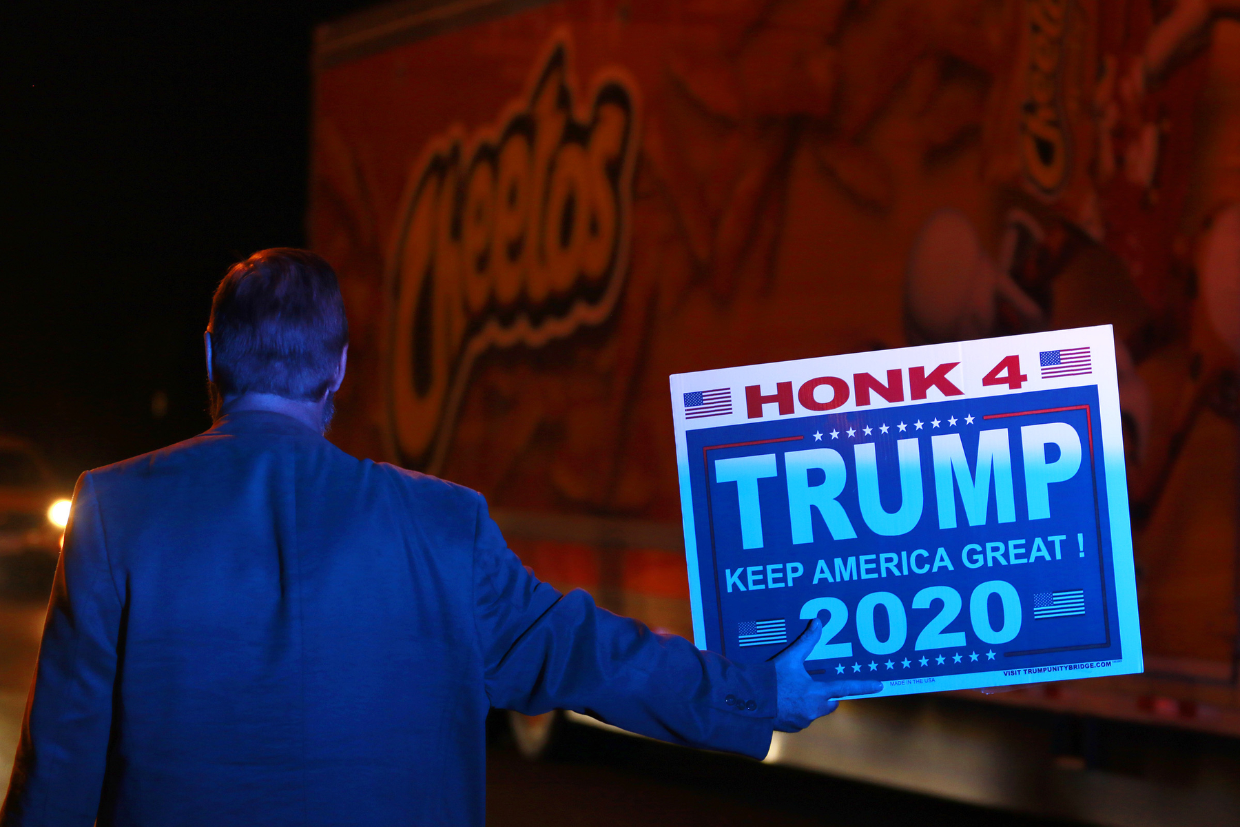 Andy Danevicius holds a sign in the street behind a parked police car that illuminates him blue and joins other Donald Trump supporters in protesting the Nevada vote outside Clark County Election Department Thursday, November 5, 2020, in North Las Vegas. Danevicius, who hails from Canada, said that he became a US Citizen last year to be able to vote in this election. (Photo by Ronda Churchill/AFP)