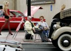 Bill Wright and his mother, Joan, socialize next to his 1936 Ford coupe at the Super Run Car Show on Water Street in Henderson, Nevada.  Behind them, a model walks by a 1961 candy apple red Chevrolet.