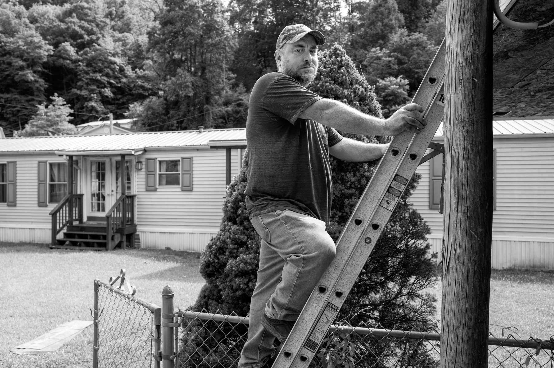 Billy Privett in Micco, West Virginia. Micco is a tiny village with only a handful of houses. I saw Billy working on this roof and stopped to ask him if he might have known the preacher I photographed in Micco years ago. I asked if he was now retired, and he responded, “Well, not exactly.” I then asked if he was on disability, assuming he’d worked in the mines. He said yes, disability, but he worked construction. His co-worker shot him accidentally in the head with a nail gun. A large 16 penny spike went 5 inches into the back of his skull. He was fully conscious, and walked himself to the local hospital. The injury was so severe they couldn’t treat him  and he was helicoptered to a larger hospital, where he stayed  overnight until a qualified surgeon arrived. After the surgery he was told if the nail had penetrated another millimeter it would have hit his spinal cord and killed him instantly. He suffers from short-term memory loss and can’t hold a job. If he needs to run errands he has to write down a list of what he is supposed to get. 