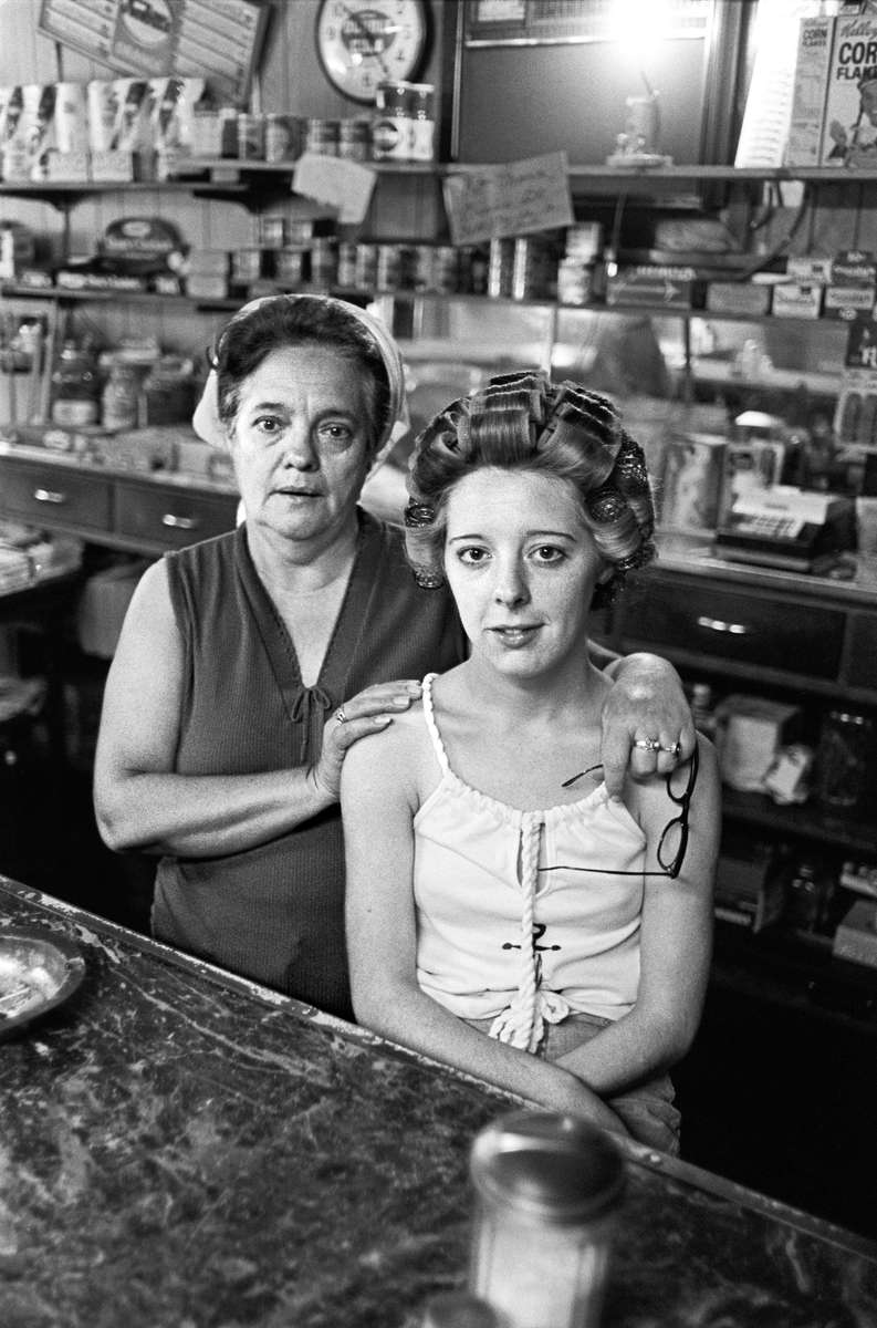Mother and daughter, Rowe Restaurant, Algoma, West Virginia, 1978. This combination restaurant/bar was like many in coal country, open early and late to serve miners working round-the-clock shifts. Men came in for beers after the graveyard shift ended, while others ate breakfast before starting work. The day I came by a fist fight broke out between two burly brothers in their late teens. A few punches were thrown, but it was quickly broken up. I was sitting with the woman pictured, whose husband was the owner. She got very teary and upset, despite no one getting hurt. When I asked why, she explained she hated to see brothers fight. She went on to relate how years earlier two brothers began fighting, and the place was getting torn up. Her husband told the brothers to stop, to no avail. He raised his shotgun from behind the bar and repeated his demand. The two charged him, and he fired his gun. Seconds later, two brothers lay dead on the barroom floor. No charges were ever brought. That was justice in the back hills of West Virginia. Jon Chase photo