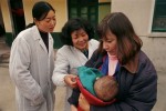 The 7-month-old child of a new adoptive parent is admired by orphanage workers at the Children's Welfare Institute in Hefei.